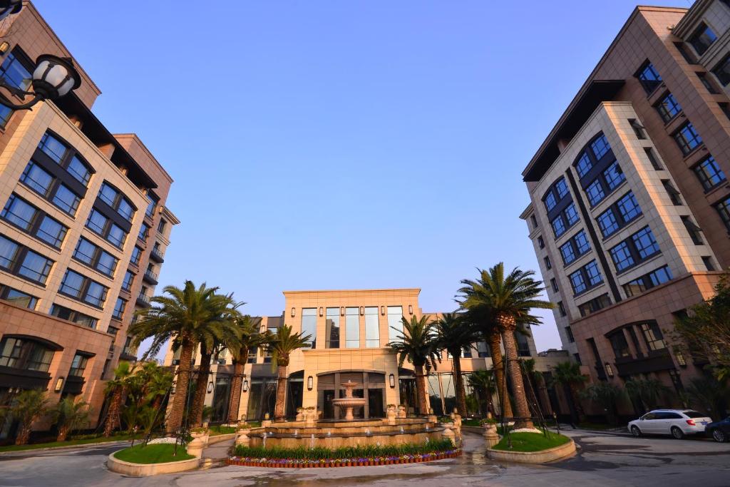 a building with palm trees in the middle of a street at Urban Island Hotel Shanghai in Jiading