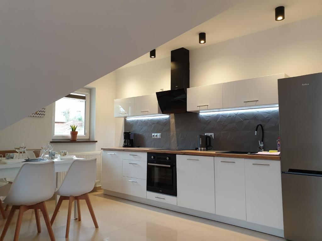 uma cozinha com armários brancos e uma mesa e cadeiras em VILLA MILA Apartamenty em Karpacz