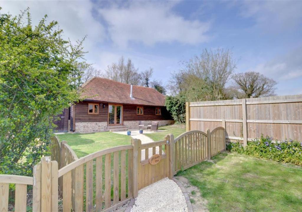 a wooden fence in front of a house at Barley Byre in Rolvenden