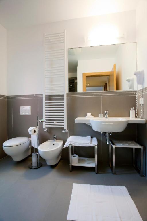 a bathroom with a sink and a toilet and a mirror at Hotel Marco Polo in Lido di Jesolo
