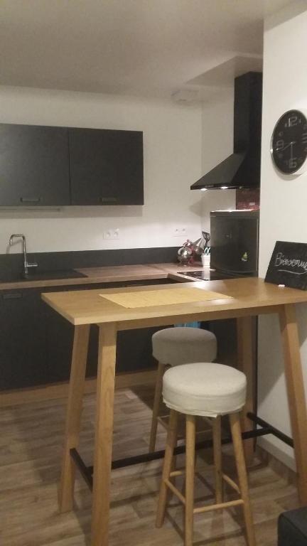une cuisine avec une table en bois et deux tabourets dans l'établissement Appartement cosy 25 m², à Limoges