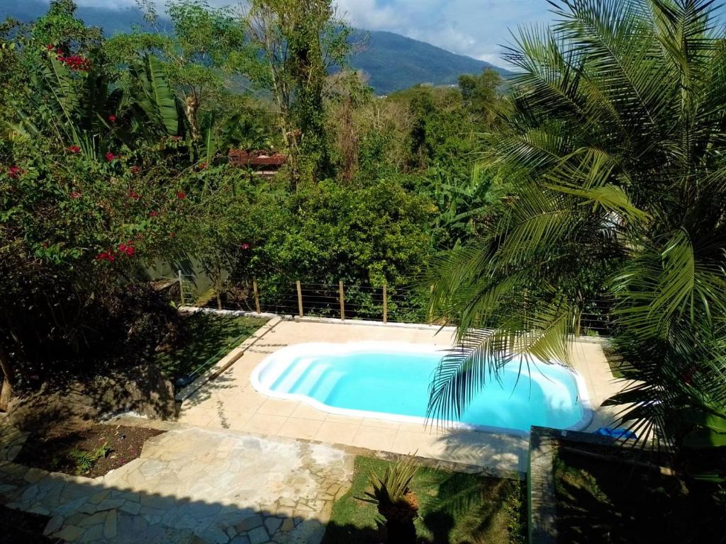 a swimming pool in the middle of a garden at Casa próxima ao mar e montanha in Ilhabela