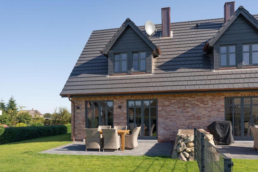 une maison avec une table et des chaises dans la cour dans l'établissement Hus Sünneck, à Wyk auf Föhr