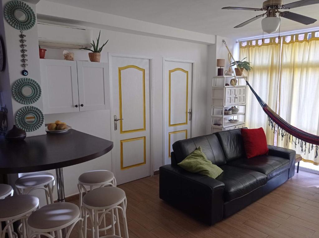 sala de estar con sofá negro y mesa en Clean and comfortable budget flat, en Fuengirola