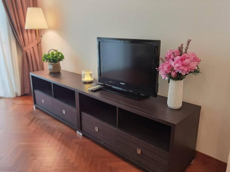 einen Flachbild-TV auf einem Entertainment-Center mit Blumen in der Unterkunft EASTERN ORIENTAL STRAIT QUAY MARINA LUXURY SUITE in Tanjong Tokong