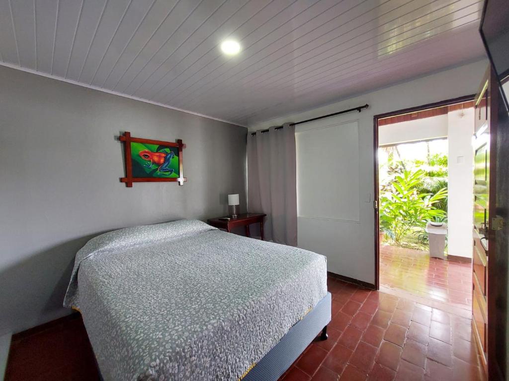 Schlafzimmer mit einem Bett und einer Glasschiebetür in der Unterkunft Hôtel Pez Gallo in Golfito
