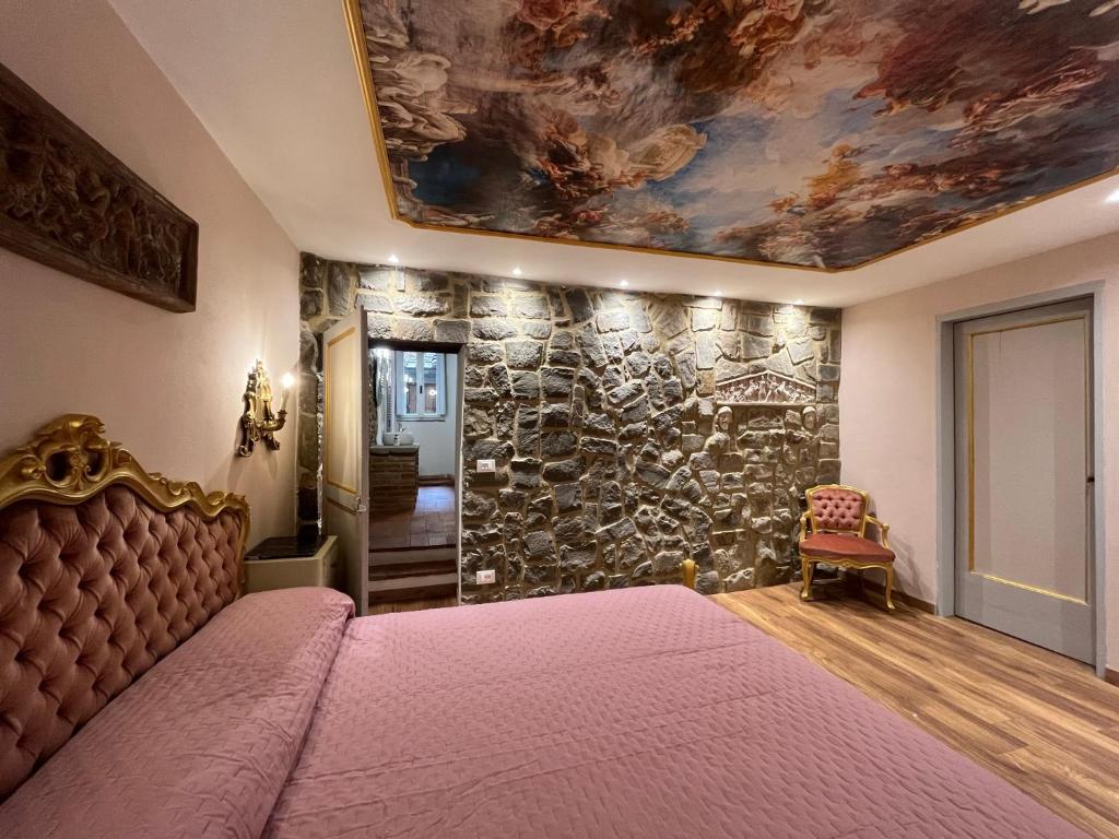 sypialnia z dużym łóżkiem i kamienną ścianą w obiekcie CORTONA SUITE - THE HOUSE WITH WELL and THE FRESCOS PALACE w mieście Cortona