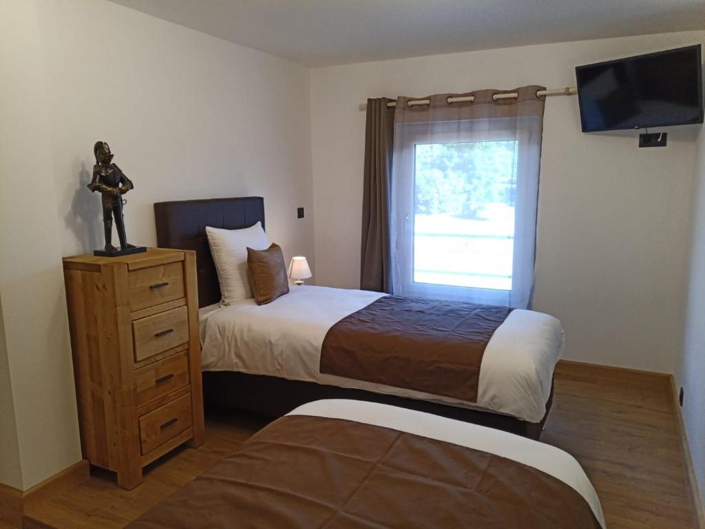 a bedroom with two beds and a window and a dresser at PAVIE in Torpes