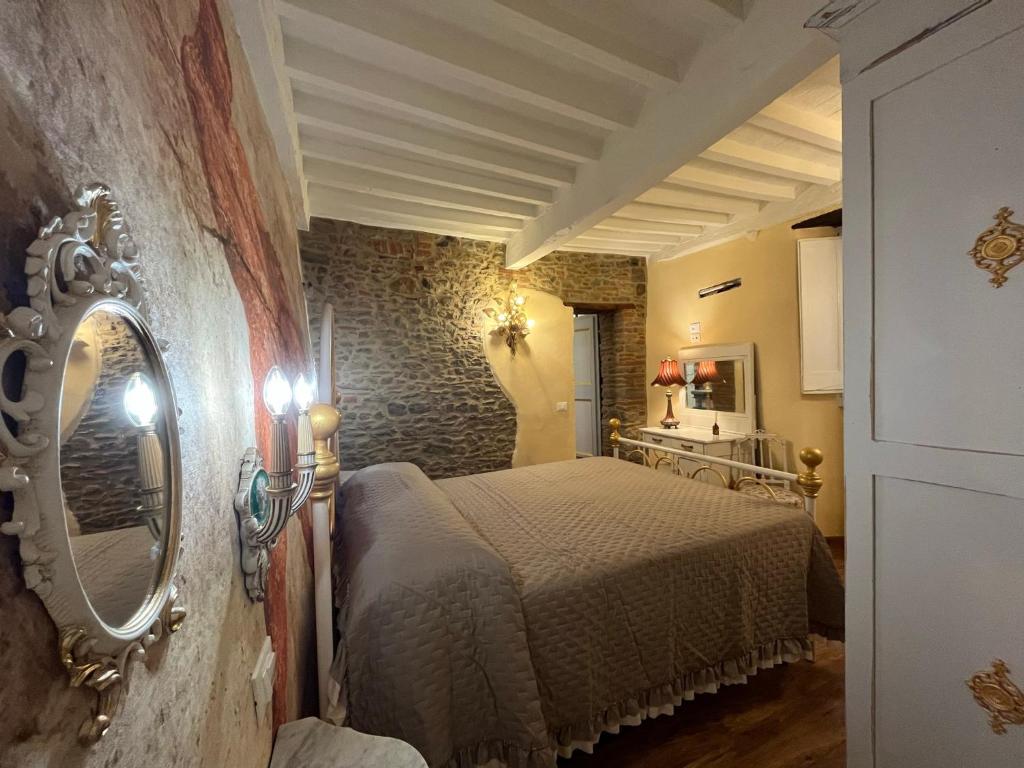 sypialnia z łóżkiem i lustrem na ścianie w obiekcie CORTONA SUITE - THE HOUSE WITH WELL and THE FRESCOS PALACE w mieście Cortona