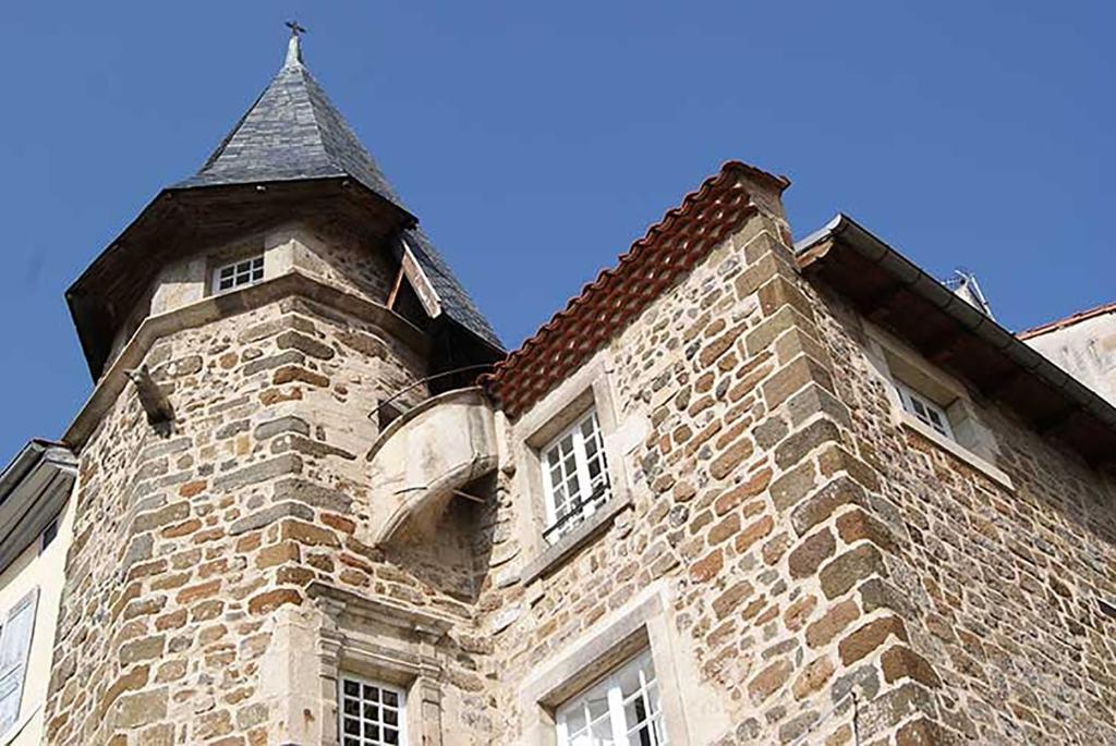 un bâtiment en briques avec une tour avec un toit dans l'établissement Maison au Loup - Superbe ancien hotel particulier du XVIe siècle au cœur de la vieille ville du Puy, au Puy-en-Velay