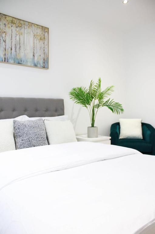 a white bedroom with a bed and a potted plant at Dee Place 2 Bedroom Luxury Apartment Royal Wharf Docklands by ExCeL Exhibition Centre London in North Woolwich