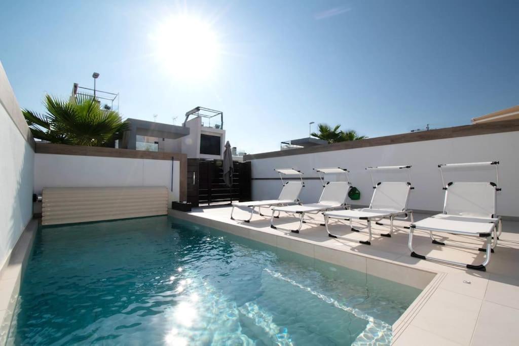 a swimming pool with chairs and a swimming pool at Magnifique villa avec piscine privée chauffée in Benijófar