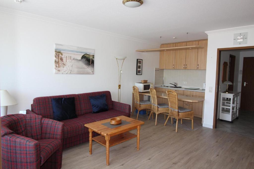 a living room with a couch and a table and a kitchen at Haus Norderhoog Wohnung 39 in Westerland