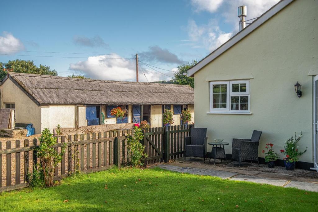 a house with a fence and a table in the yard at Monks Cleeve Bungalow in Exford