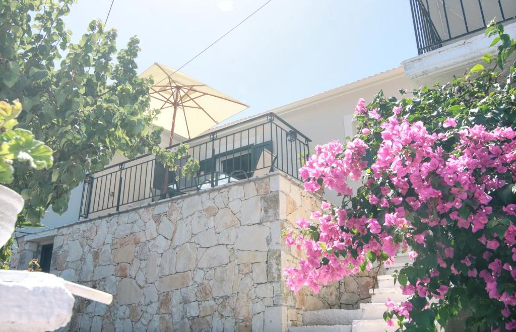 a house with pink flowers on a stone wall at Fiskardo Beach House in Fiskardo