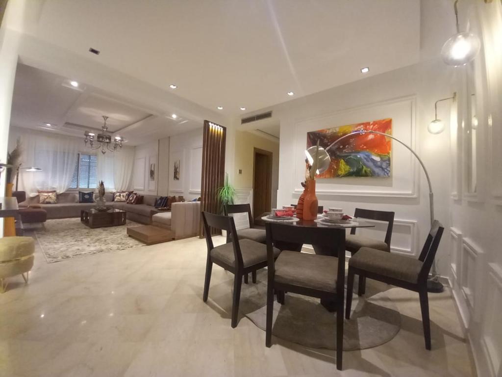 a dining room and living room with a table and chairs at Appartement la perle de Nouaceur in Nouaceur