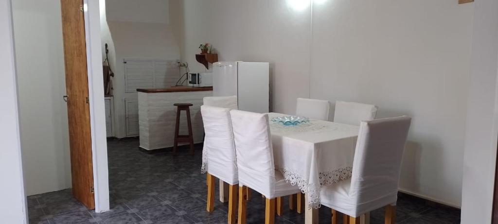 a dining room with a table and white chairs at Alojamiento El Coco in Puerto Madryn