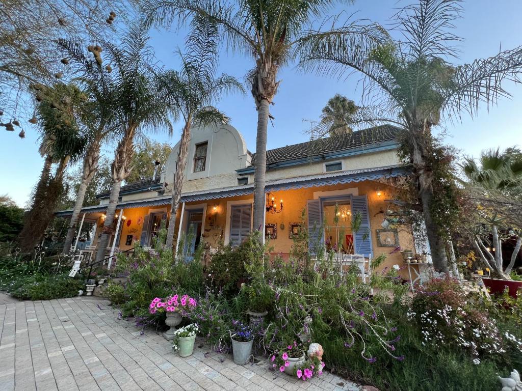 a house with palm trees and flowers in front of it at Yellow Aloe in Clanwilliam