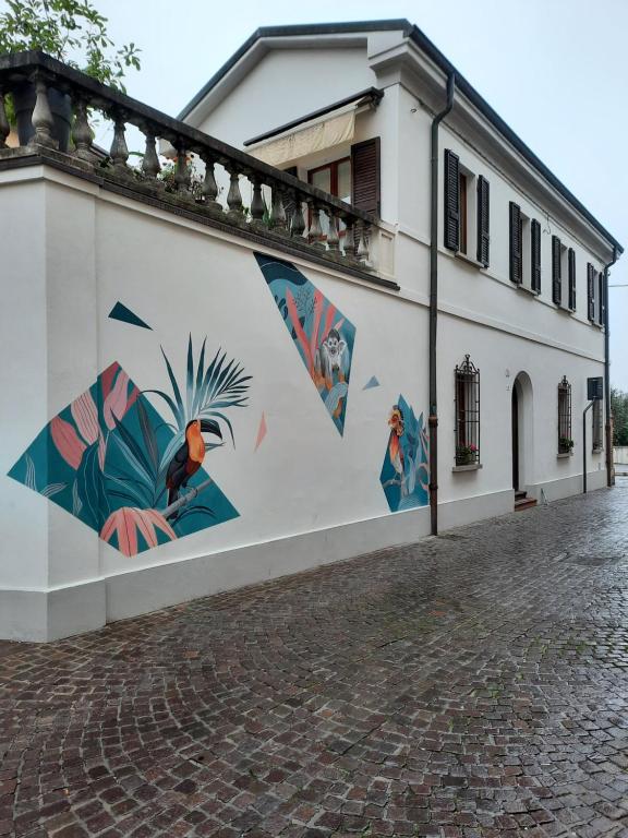 ein weißes Gebäude mit Gemälden auf der Seite in der Unterkunft b&b del vicolo in Cesena