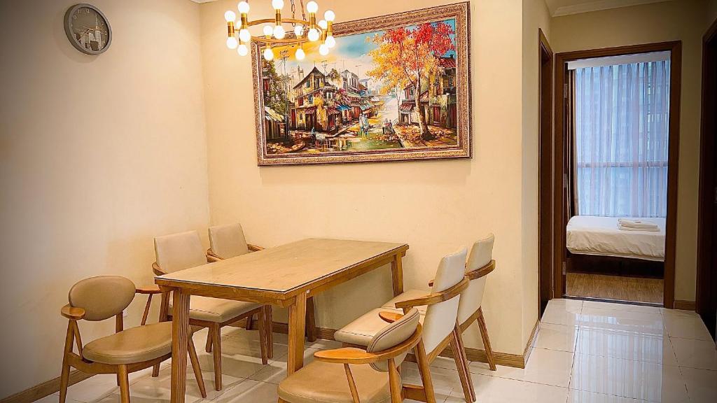 une table à manger avec des chaises et un tableau mural dans l'établissement Căn hộ Vinhomes Central Park- CityLights Premium Apartment, à Hô-Chi-Minh-Ville
