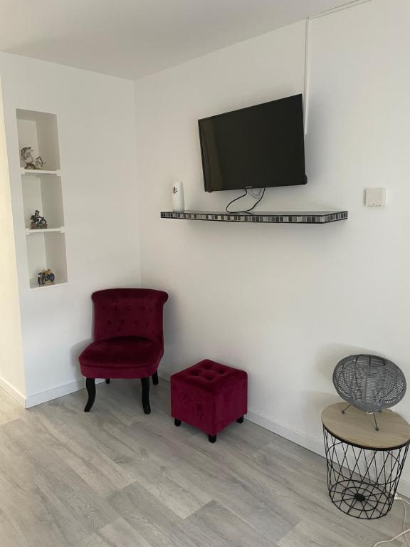 a living room with a red chair and a flat screen tv at Au cœur des Vosges in Saint-Étienne-lès-Remiremont