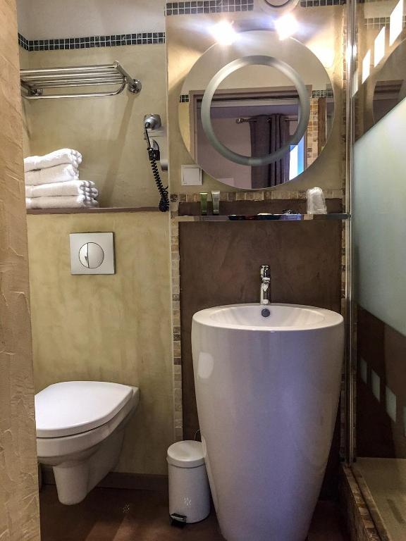 a bathroom with a sink and a toilet and a mirror at Le Belvedere in Vallon-Pont-dʼArc