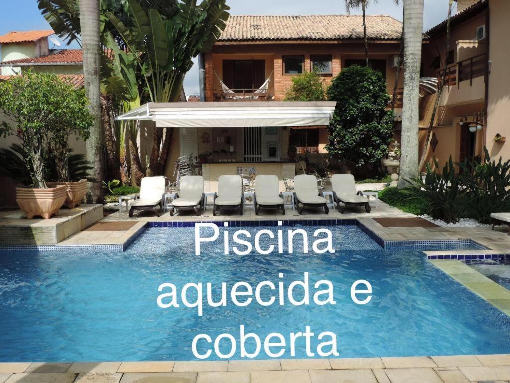 een zwembad met een bord met pisaacco analgesica colombo bij Hotel Costa Balena-Piscina Aquecida Coberta in Guarujá