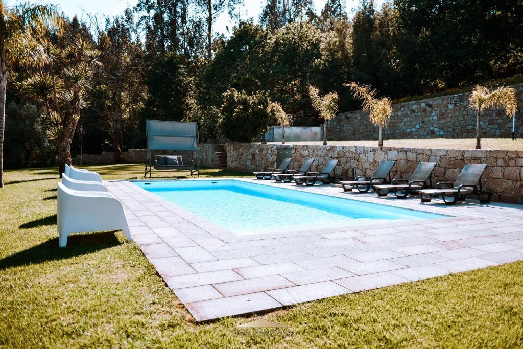 a swimming pool with lounge chairs next to a stone wall at Casa Lima Braga in Braga