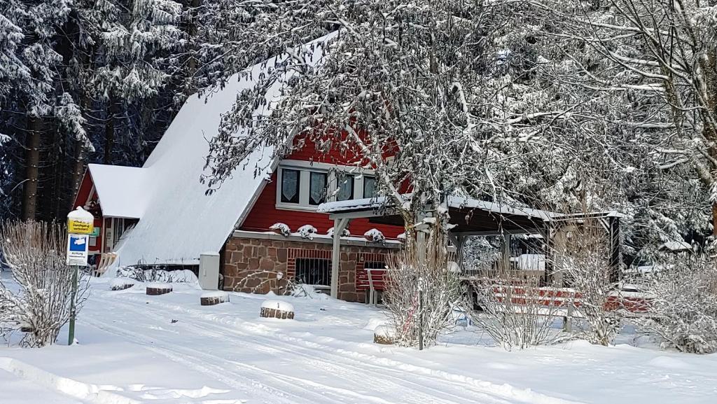 ein rotes Haus im Schnee mit schneebedeckten Bäumen in der Unterkunft Wanderhütte Zum Bernhardsthal in Bernhardsthal