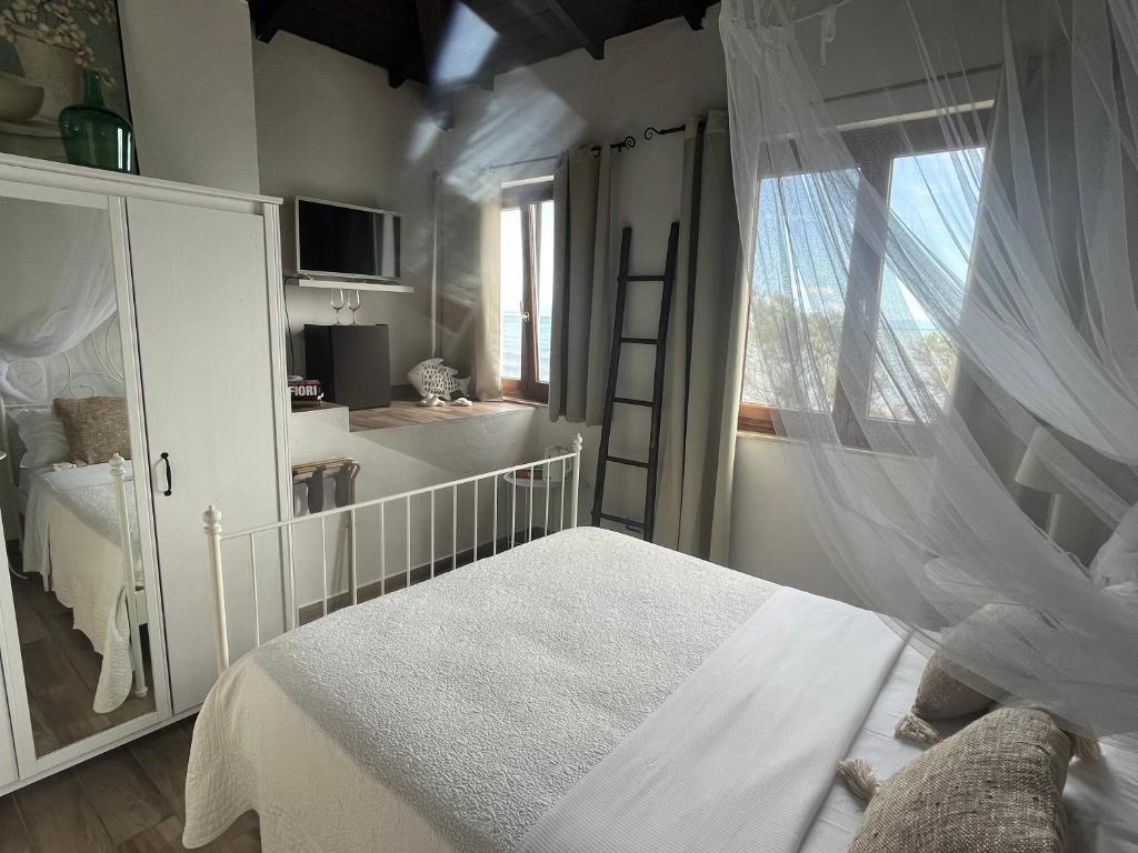 - une chambre blanche avec un lit et une fenêtre dans l'établissement La Casa di Nina, à La Maddalena