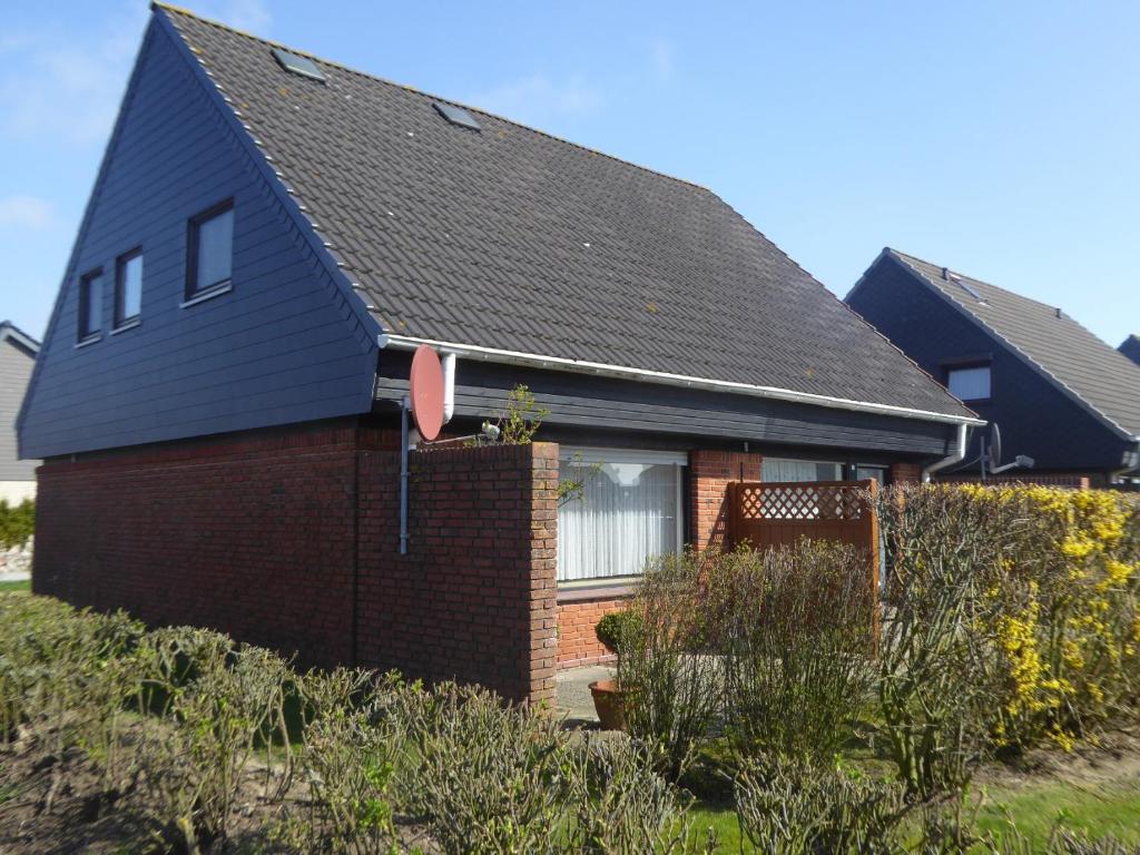 une maison avec un toit noir et un mur de briques dans l'établissement Hus Waterkant, à Friedrichskoog