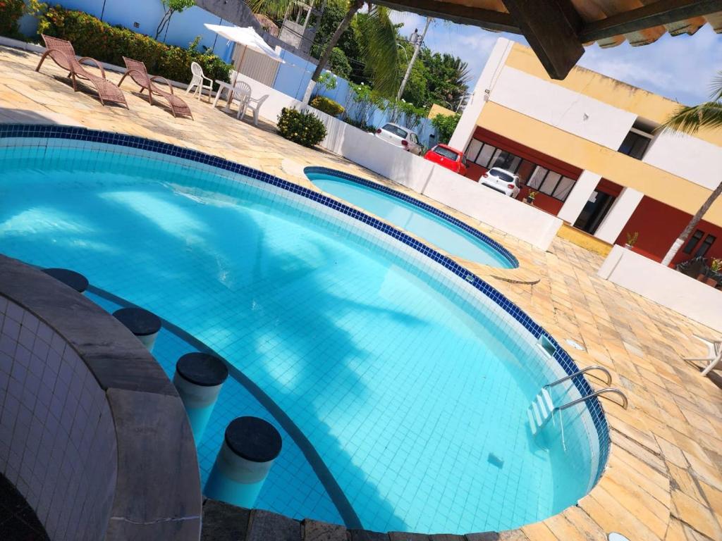 a swimming pool with blue water in a resort at Apartamento único na praia do Farol de Itapuã in Salvador