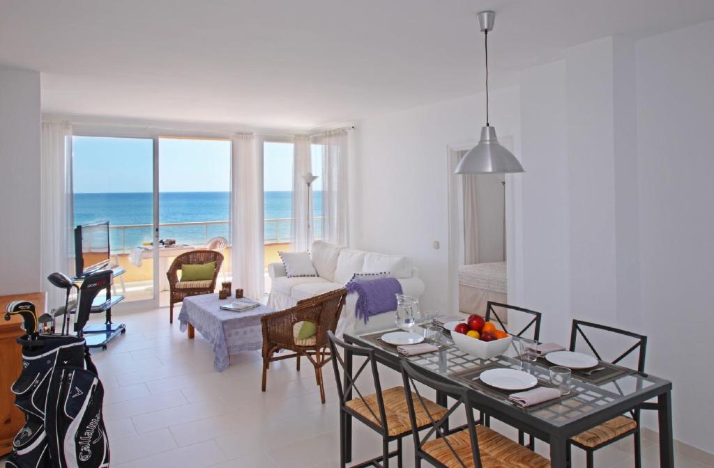 una sala de estar con mesa y sillas y el océano en Apartamentos Golf Mar by La Costa Resort, en Pals