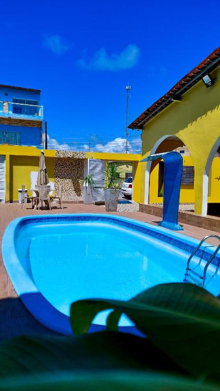a large blue swimming pool in front of a house at Pousada Gamela do Maragogi in Maragogi