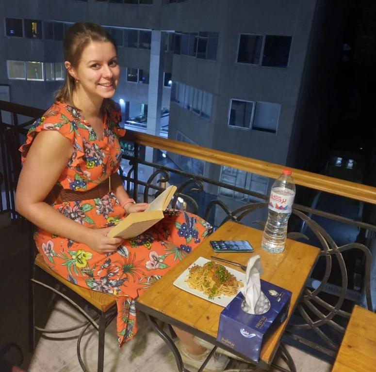 Paris Hotel Cairo في القاهرة: امرأة تجلس على طاولة تقرأ كتابا