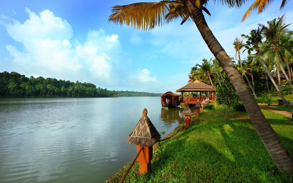 Blick auf einen Fluss mit einem Haus und Palmen in der Unterkunft Fragrant Nature Backwater Resort & Ayurveda Spa Kollam in Kollam