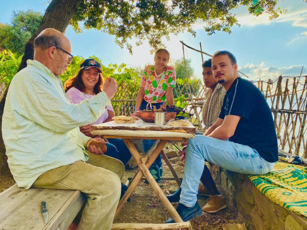 un grupo de personas sentadas alrededor de una mesa de picnic en Le Sommet Naturel, en Chefchaouen