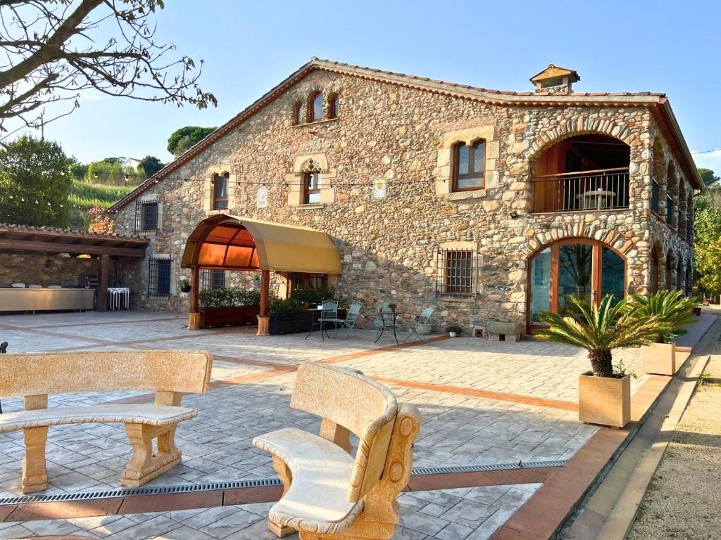 un edificio de piedra con dos bancos delante en Mas Segart en Santa María de Palautordera