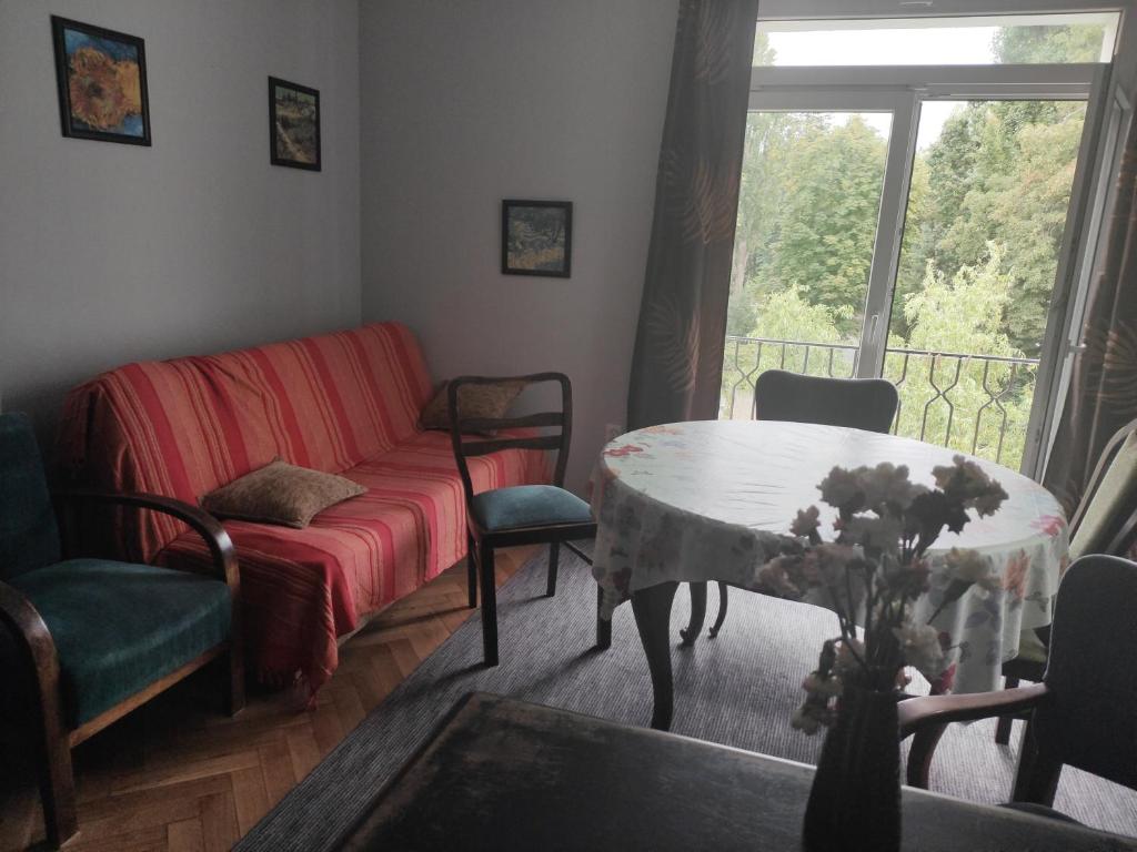 uma sala de estar com um sofá, uma mesa e uma janela em Stary Mokotów, blisko metra em Varsóvia