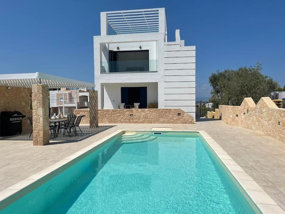 a villa with a swimming pool in front of a house at Souvala /Aegina. Excellent location Luxury villa. in Vathí