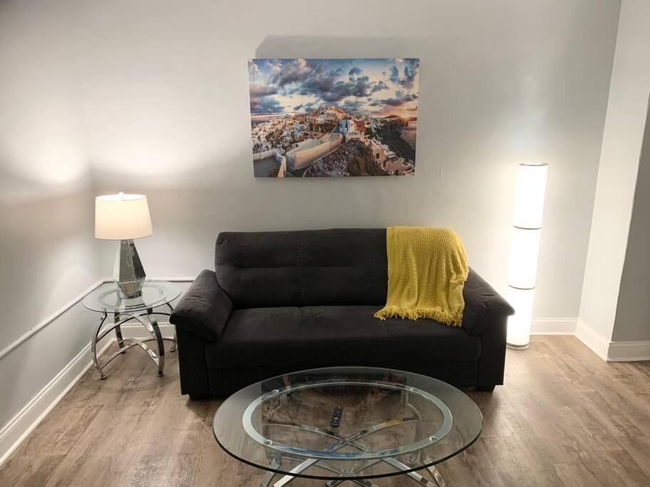 ein Wohnzimmer mit einem schwarzen Sofa und einem Glastisch in der Unterkunft Modern cozy 1BD/1BA Apt in Federal Hill in Baltimore