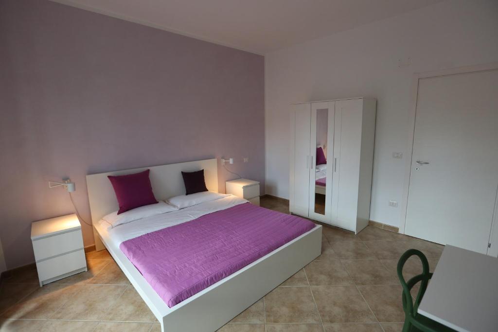 1 dormitorio con 1 cama grande con manta morada en Casa Michela, en LʼAquila