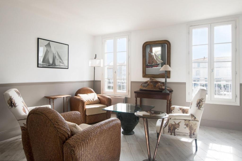 een woonkamer met stoelen, een tafel en een spiegel bij Appartement L'Îlot au centre du port de Saint Martin in Saint-Martin-de-Ré