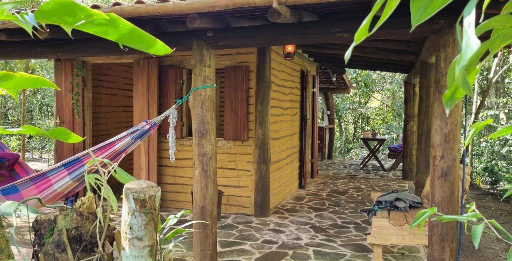 una hamaca frente a una cabaña de madera en Chalé O Canto dos Pássaro, en Paraty