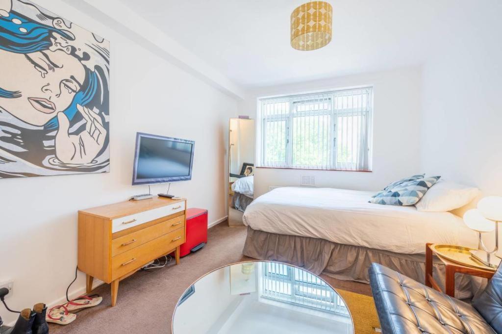 sypialnia z łóżkiem, telewizorem i kanapą w obiekcie Flat 13 w Londynie