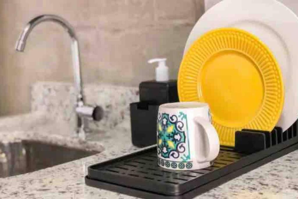 a coffee mug sitting on a kitchen counter with a plate and a sink at 92 New studio next Paulista Av, fast wifi and balcony in Sao Paulo