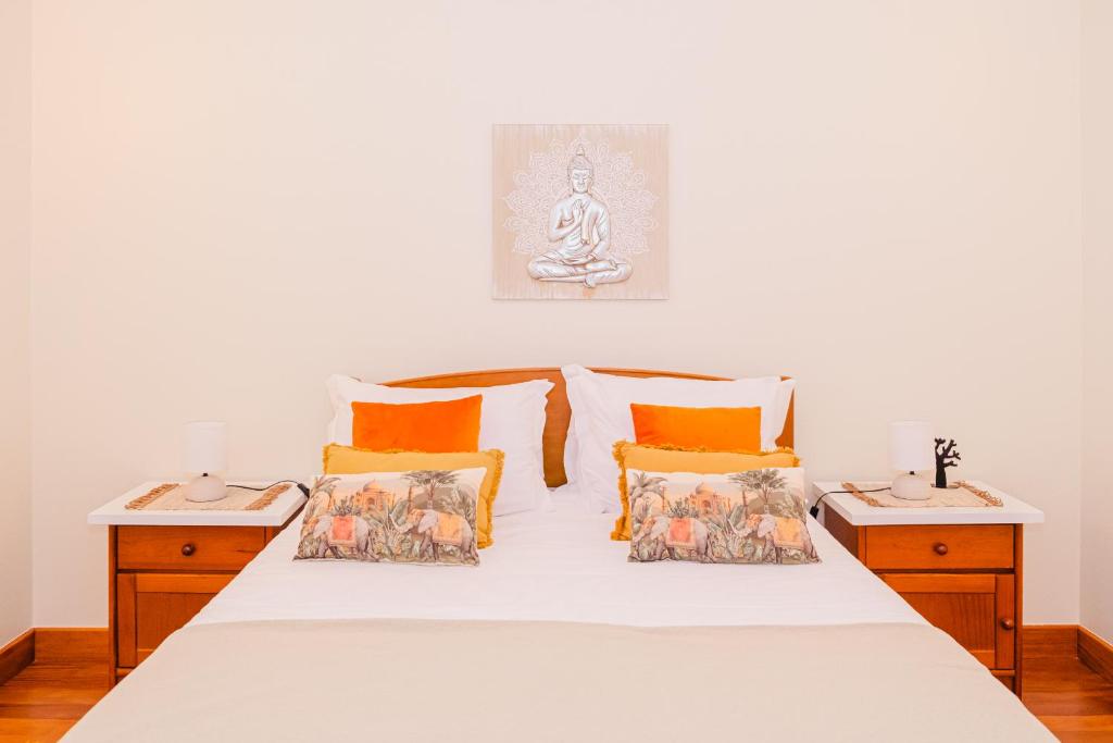 a bedroom with a white bed with orange pillows at Namastê House I in Relógio do Poiso