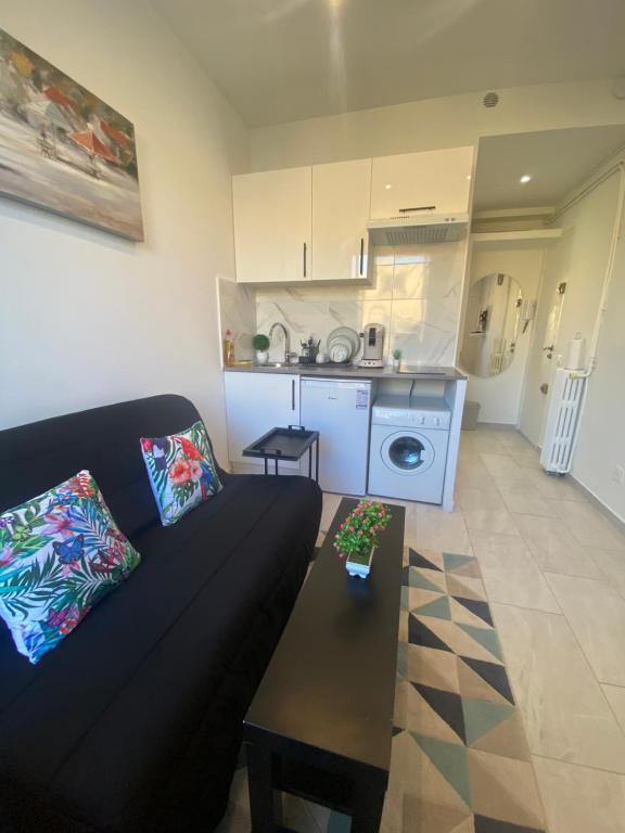 a living room with a black couch and a kitchen at Studio sur avenue jean médecin à Nice in Nice