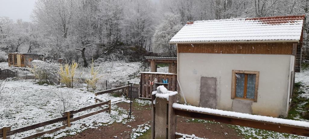 a house covered in snow next to a fence at Gîte de charme avec jacuzzi étang babyfoot et rivière 