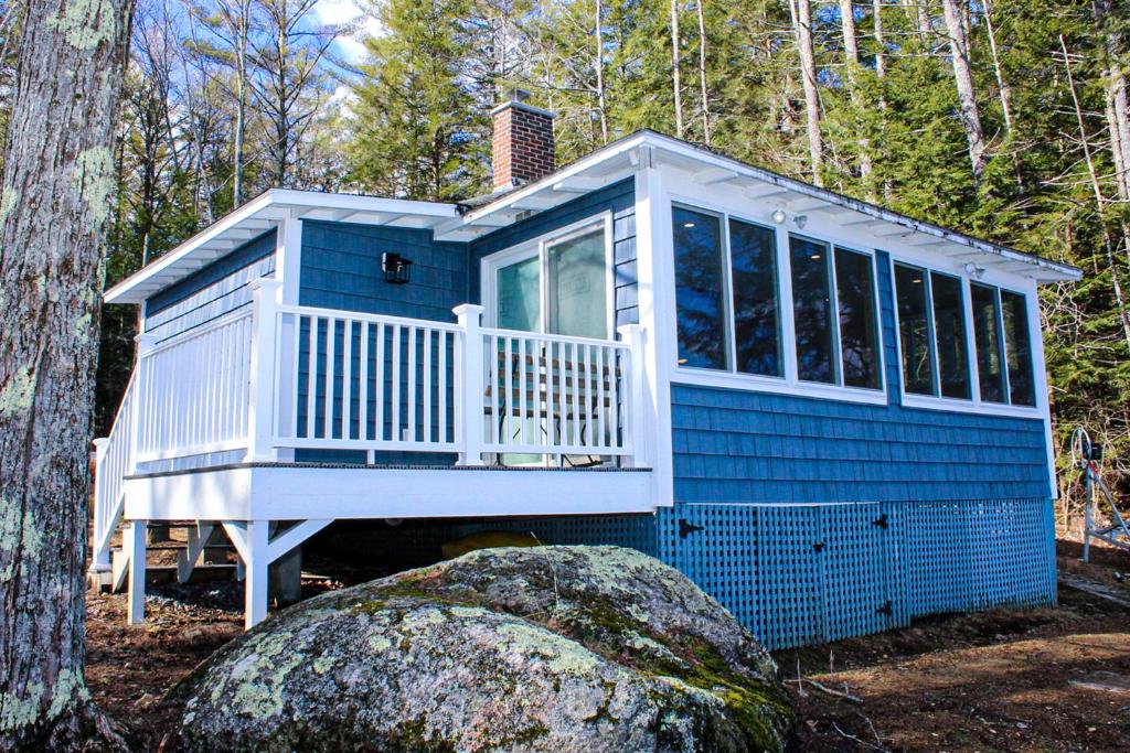a blue tiny house in the woods at Lake Winnisquam Getaway in Sanbornton